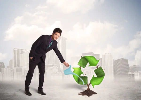 Hombre de negocios riego verde reciclar árbol signo en el fondo de la ciudad — Foto de Stock