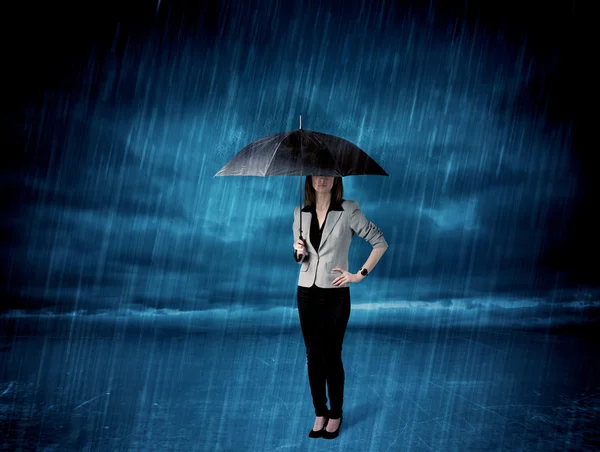 Business woman standing in rain with an umbrella — Stock Photo, Image