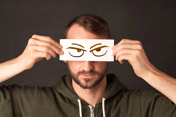 Young person holding paper with angry eye drawing — Stock Photo, Image