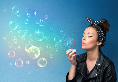 Mavi arka planda renkli kabarcıklar çıkaran güzel bayan.