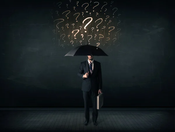Empresário com guarda-chuva e um monte de pontos de interrogação desenhados — Fotografia de Stock