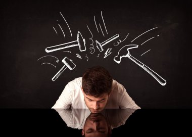 Depresyondaki işadamı çekiç izlerinin altında oturuyor
