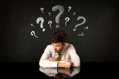 Soru işaretleri altında oturan işadamı