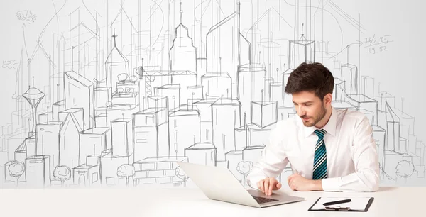 Biznesmen siedzi przy białym stole z ręcznie rysowanymi budynkami — Zdjęcie stockowe