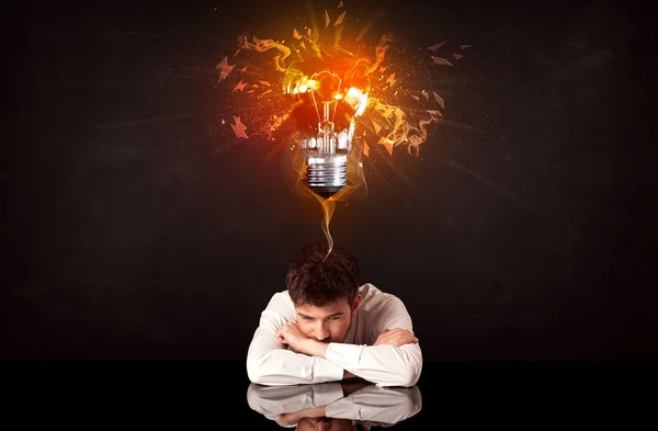 Businessman sitting under a blowing idea bulb — Stock Photo, Image