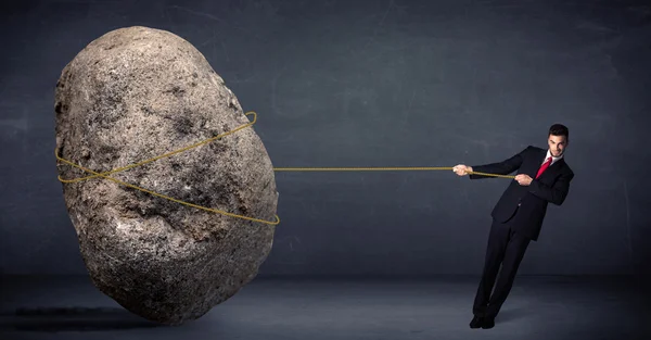 Businessman pulling huge rock with a rope — Stock Photo, Image