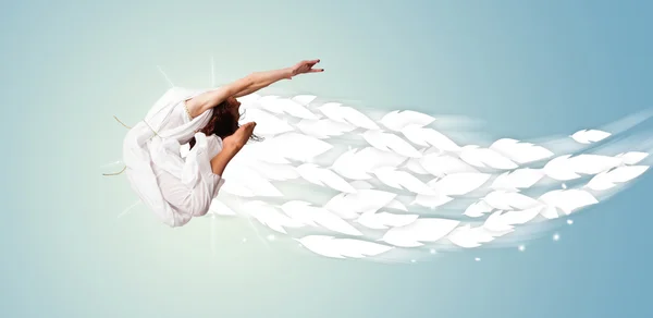 Healthy young woman jumping with feathers around her — Stock Photo, Image