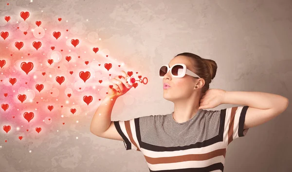 Pretty young girl blowing red heart symbols — Stock Photo, Image