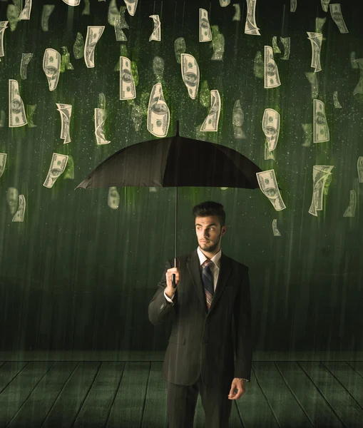 Bir dolar yağmur konseptinde şemsiyesi olan bir iş adamı