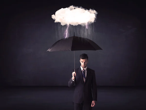 Empresario de pie con paraguas y pequeña nube de tormenta — Foto de Stock