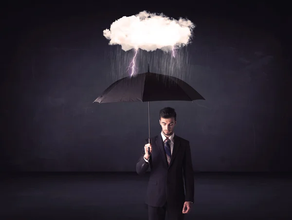 Uomo d'affari in piedi con ombrello e piccola nuvola tempesta Foto Stock Royalty Free