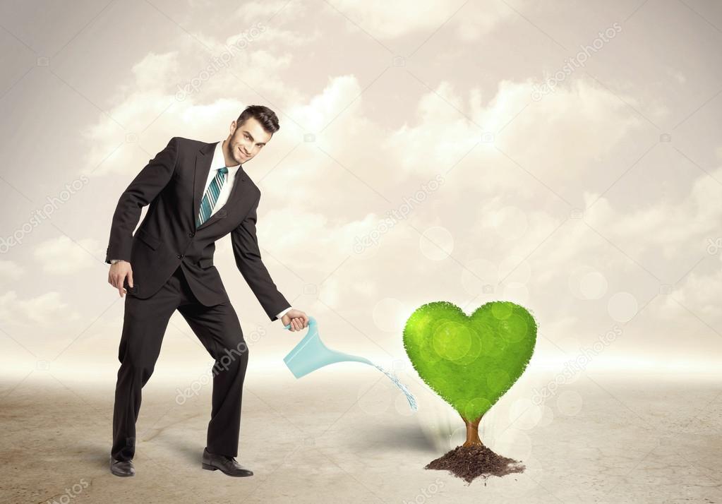 Business man watering heart shaped green tree