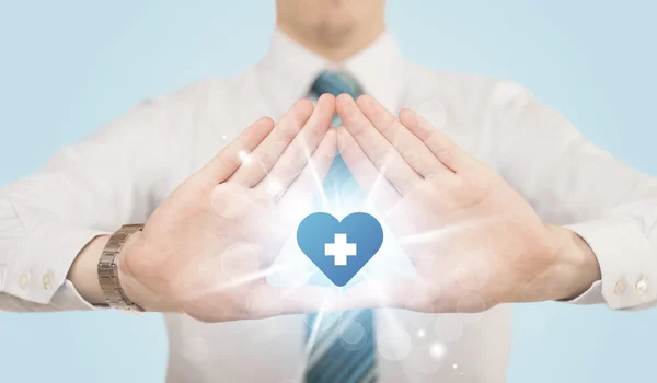 Mani che creano una forma con croce blu cuore — Foto Stock