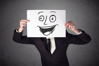 empresario sosteniendo una cartulina con cara sonriente en él en frente 