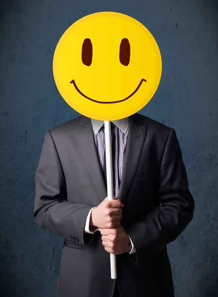 Empresario sosteniendo un emoticono sonriente —  Fotos de Stock