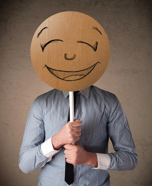 Affärsman som innehar en smiley face styrelse — Stockfoto