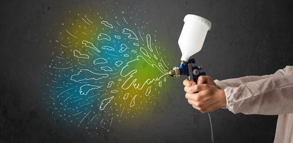 Trabajador con aerografo pistola pinta líneas de colores y salpicaduras — Foto de Stock