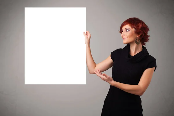 Giovane donna che presenta spazio copia su carta bianca — Foto Stock