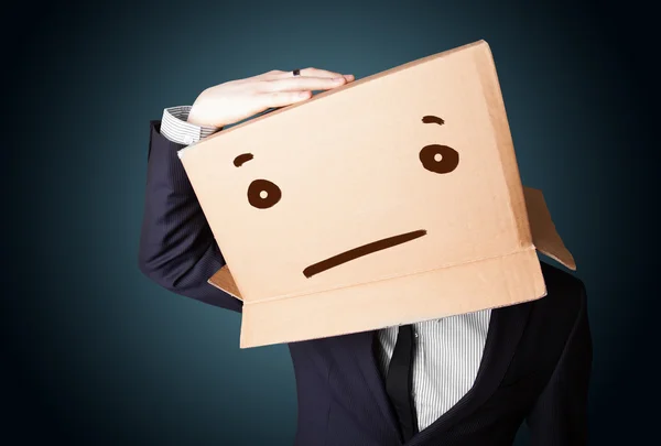 Businessman gesturing with a cardboard box on his head with stra — Stock Photo, Image