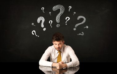 Soru işaretleri altında oturan işadamı