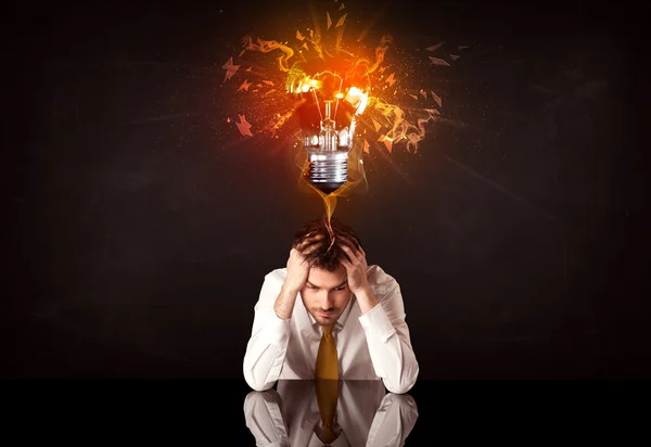 Businessman sitting under a blowing idea bulb — Stock Photo, Image