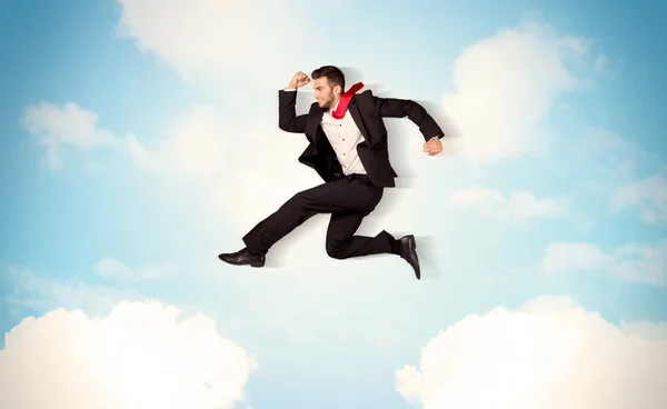 Business person jumping over clouds in the sky — Stock Photo, Image