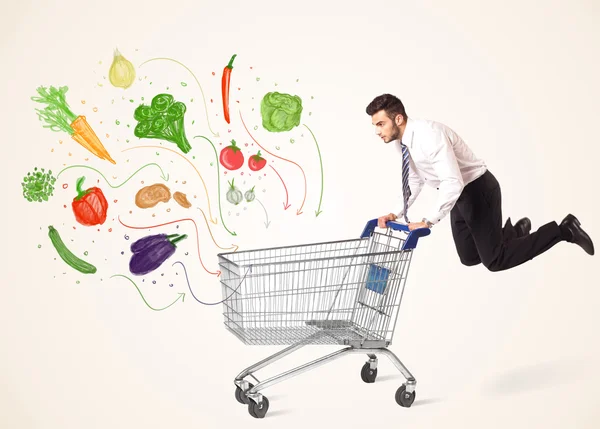 Businessman with shopping cart with vegetables — Stock Photo, Image