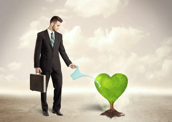 Biznes człowiek podlewanie serca w kształcie zielonego drzewa — Zdjęcie stockowe