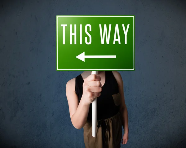 Young woman holding a direction sign — Stock Photo, Image