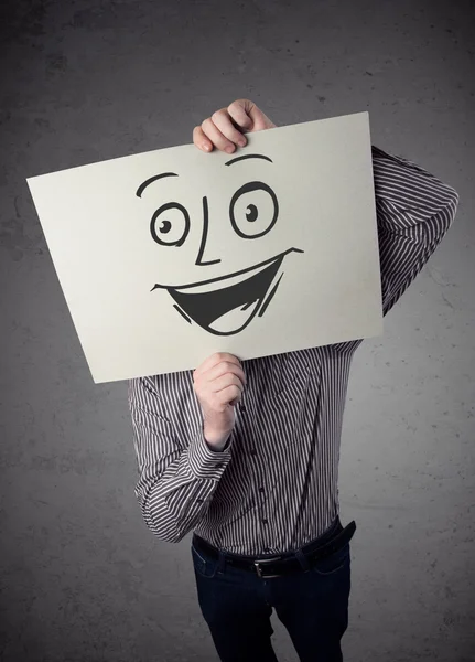 Businessman holding a cardboard with smiley face on it in front — Stock Photo, Image