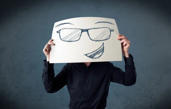 Empresário segurando um papel com rosto sorridente na frente de sua hea — Fotografia de Stock