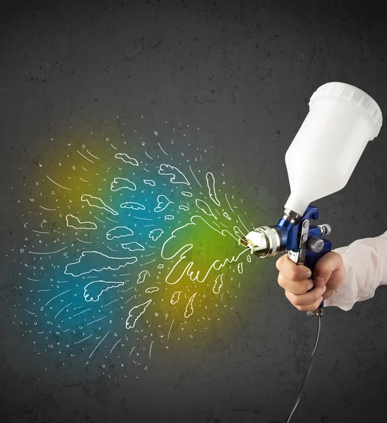 Worker with airbrush gun paints colorful lines and splashes — Stock Photo, Image