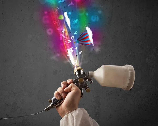 Worker with airbrush and colorful abstract clouds and balloons — Stock Photo, Image