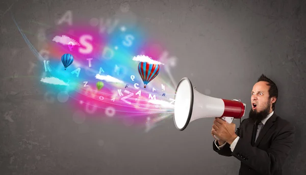 Man shouting into megaphone and abstract text and balloons come — Stock Photo, Image