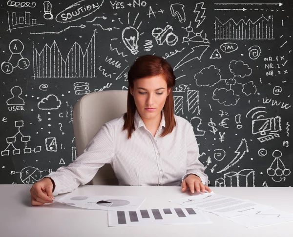 Businesswoman sitting at desk with business scheme and icons — Stock Photo, Image