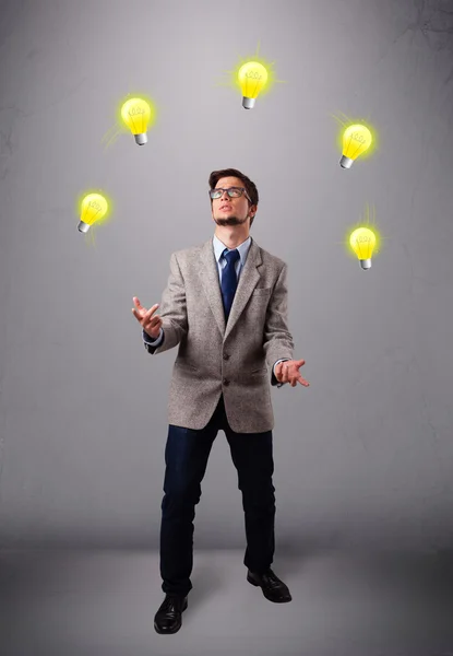 Joven de pie y haciendo malabares con bombillas — Foto de Stock