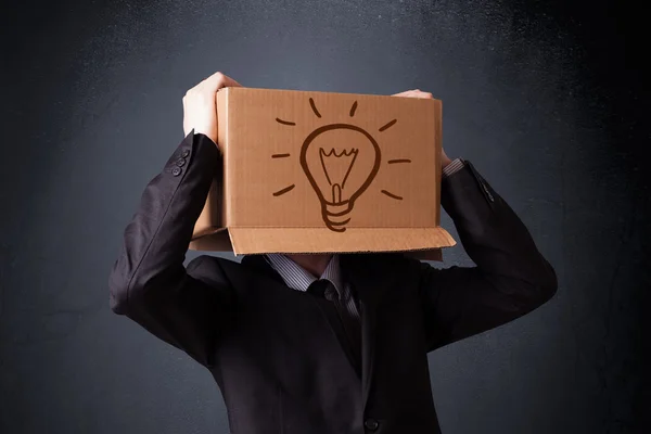 Businessman gesturing with a cardboard box on his head with ligh — Stock Photo, Image