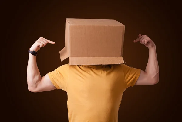 Young man gesturing with a cardboard box on his head — Stock Photo, Image