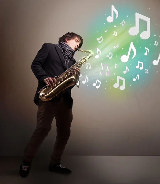 Joven músico tocando el saxofón mientras las notas musicales explotan —  Fotos de Stock