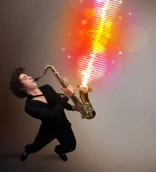 Junger Mann spielt auf Saxofon mit bunten Schallwellen — Stockfoto