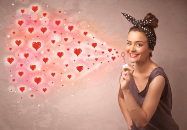 Güzel genç kız kırmızı kalp sembolleri üflüyor. 