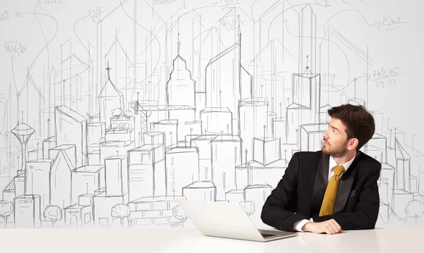 Üzletember ül a fehér asztalnál kézzel rajzolt épületekkel — Stock Fotó