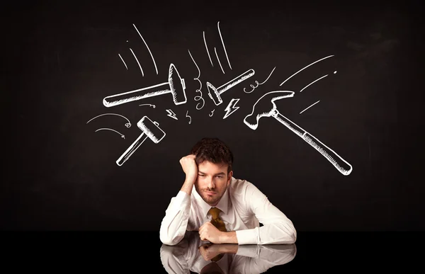 Depressed businessman sitting under hammer marks — Stock Photo, Image