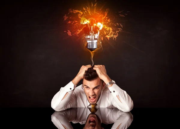 Businessman sitting under a blowing idea bulb — Stock Photo, Image