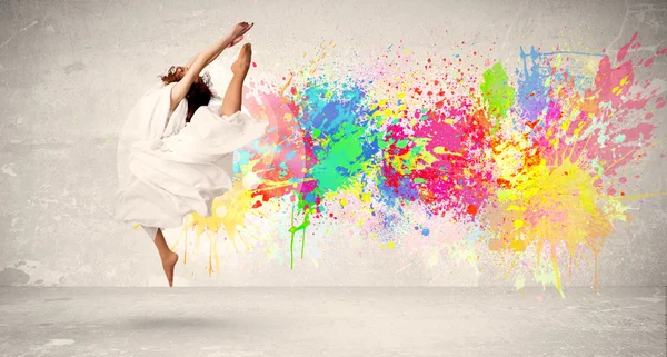 Feliz adolescente saltando con salpicaduras de tinta de colores en el respaldo urbano —  Fotos de Stock