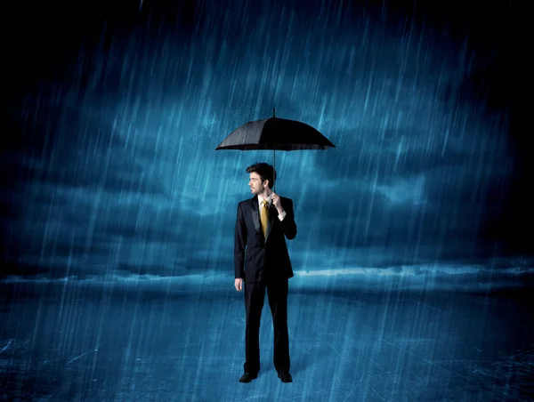 Hombre de negocios de pie bajo la lluvia con un paraguas — Foto de Stock