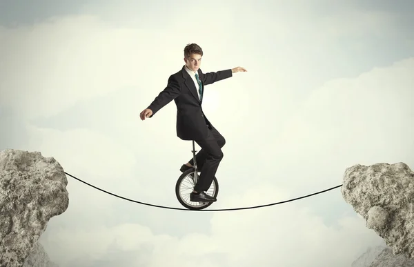 Brave business man riding an mono cycle between cliffs — Stock Photo, Image