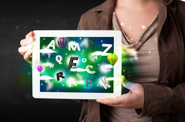 Ung person visar tablett med abstrakta bokstäver och himmel — Stockfoto