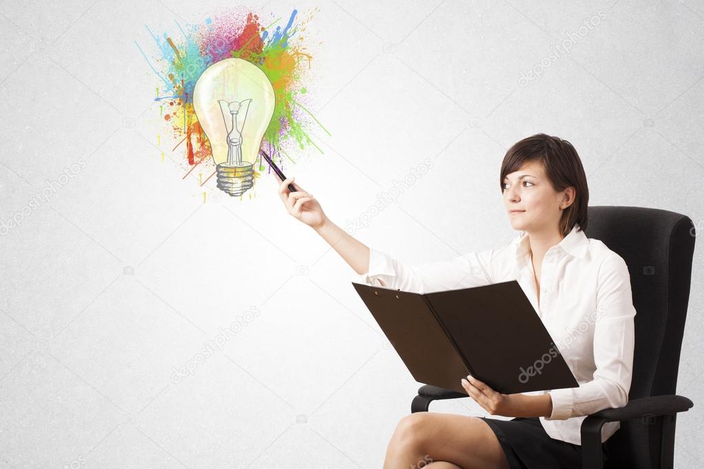 Young lady drawing a colorful light bulb with colorful splashes