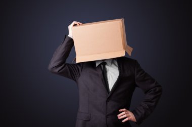 İş adamı kafasında karton bir kutuyla el kol hareketi yapıyor.